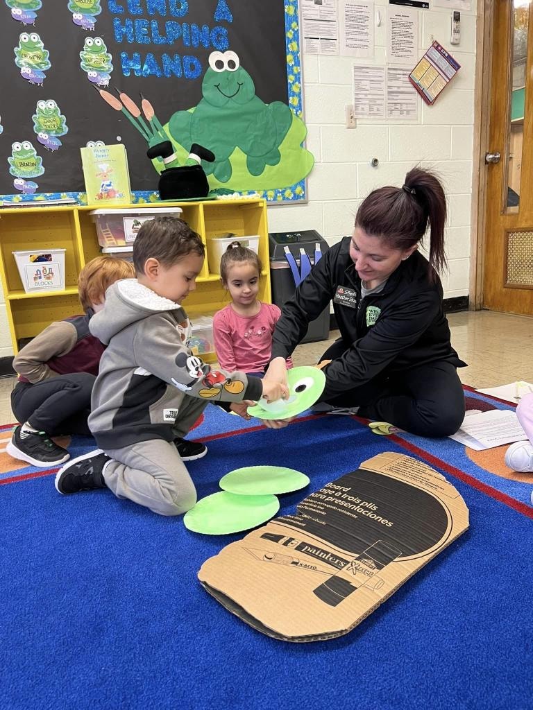 Teacher playing cornhole game with children
