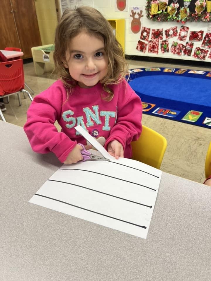 Young girl writing on lined paper in classroom